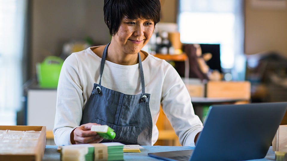Woman wearing apron looking at laptop Woman using UPS Delivery Intercept on her laptop