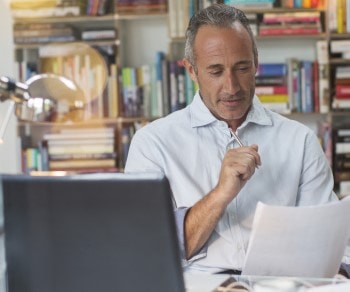 Knowledge Business casual man in home office holding a document and pen