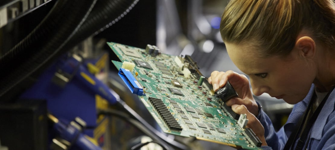 Technician inspecting motherboard at electronics factory