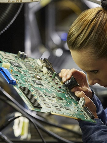 Technician inspects motherboard in warehouse