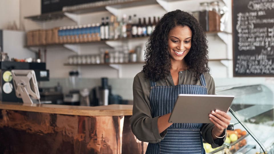 Smiling woman working in restaurant, on tablet.&nbsp;